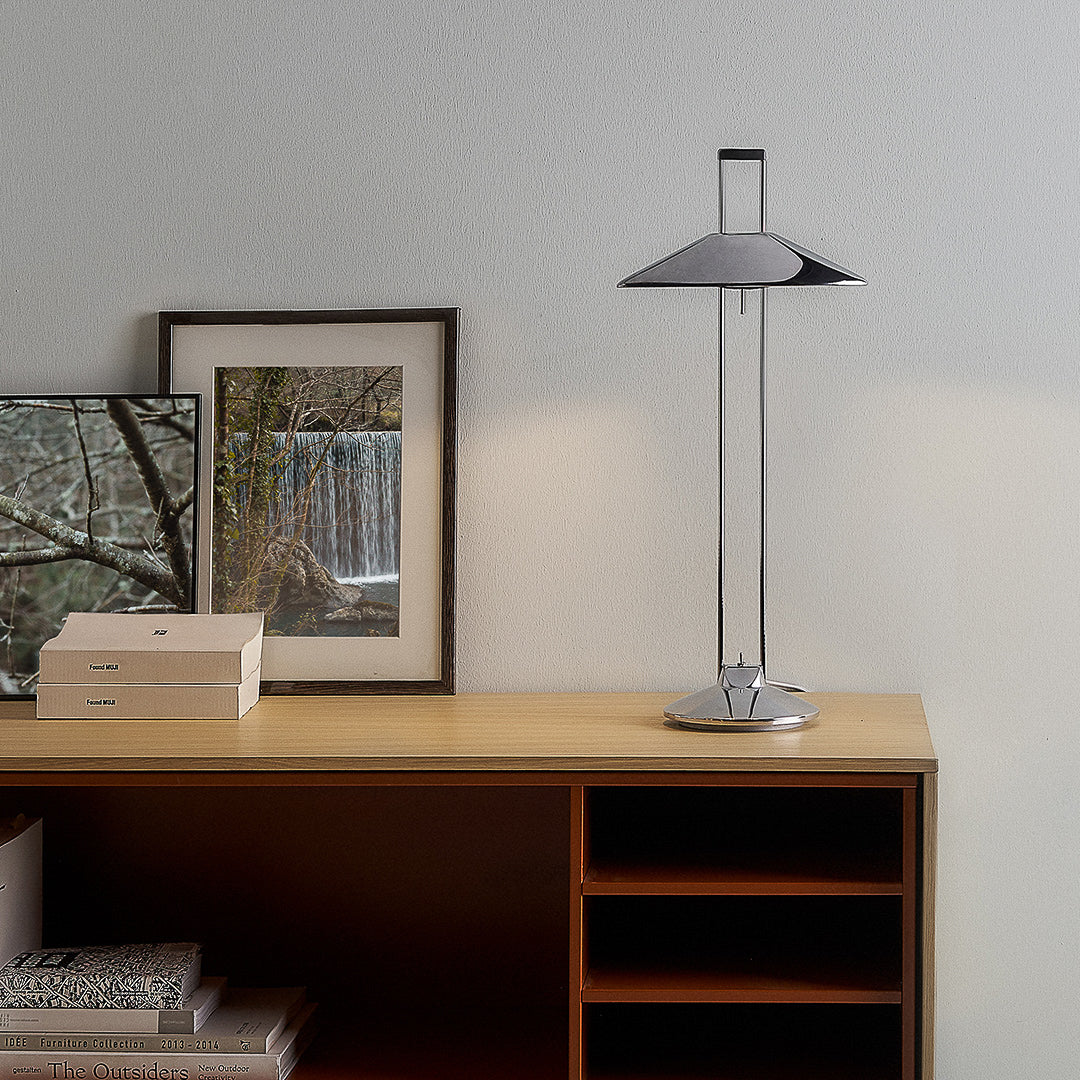 Adjustable metal table lamp on sideboard with books and pictures