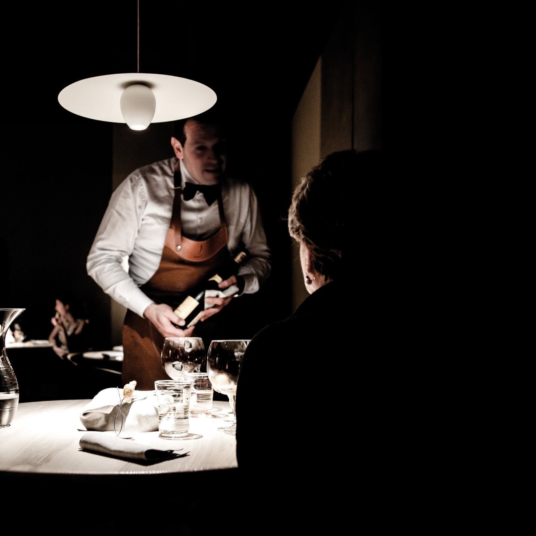 Pendant light over a table with waiter and wine glasses